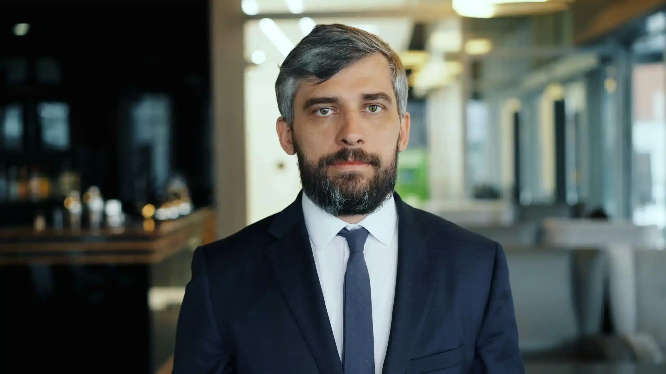 A man with a beard, dressed in a suit, poses in a professional office of Hisabatk Accounting Firm in UAE